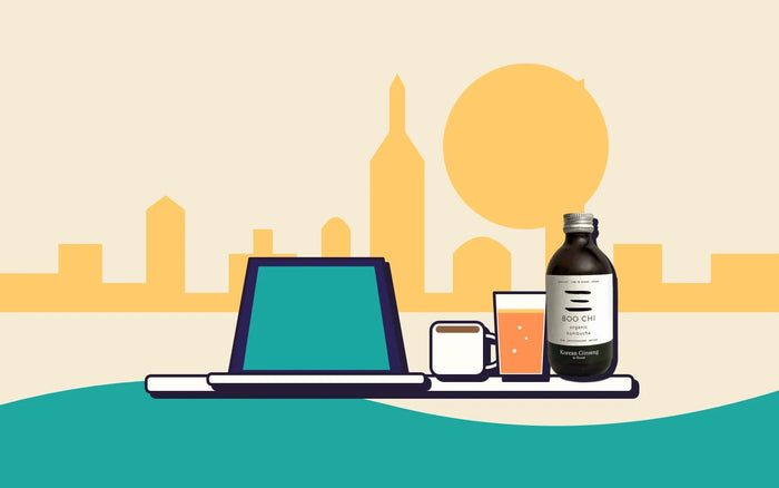 A laptop, a coffee and a bottle of kombucha in front of a Leeds skyline