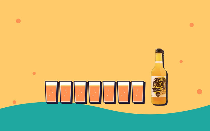 Seven small glasses of kombucha in a row, one for each day, next to a bottle of Blighty Booch