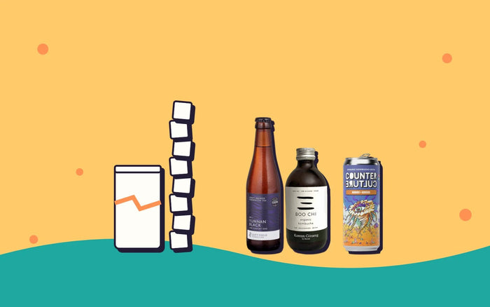 A tall stack of sugar cubes next to three bottles of kombucha