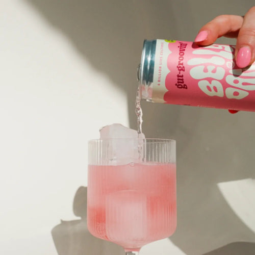 Belly Dance Cherry Berry water kefir being poured from the can into a glass of ice.