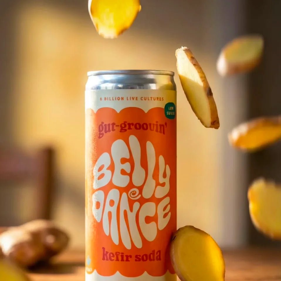 A can of Belly Dance Fiery Ginger water kefir with slices of fresh ginger falling around it.