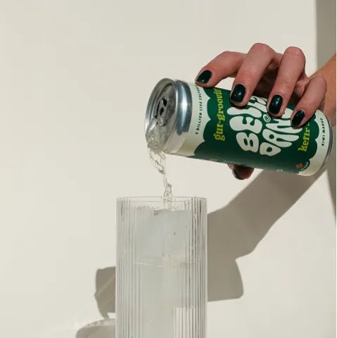 Belly Dance Kiwi Mango water kefir being poured from the can into a ribbed glass of ice.