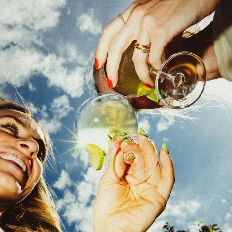 Belly Dance Spicy Margarita water kefir being poured into a coupe glass with a lime wedge against a blue sky.