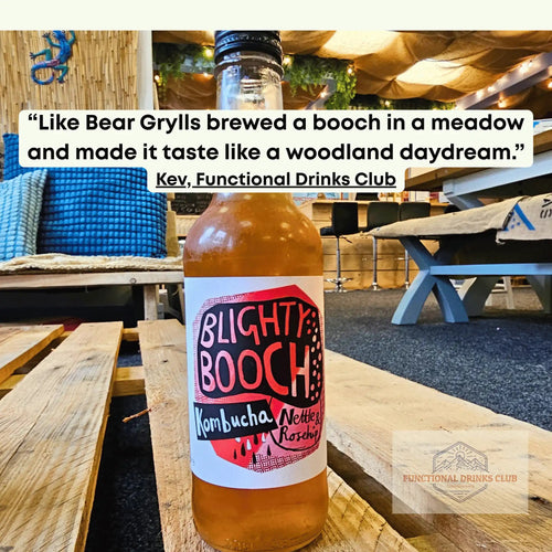 Blighty Booch Nettle & Rosehip raw kombucha on a wooden pallet table in the Otley taproom, with Kev's tasting note: "Like Bear Grylls brewed a booch in a meadow and made it taste like a woodland daydream."