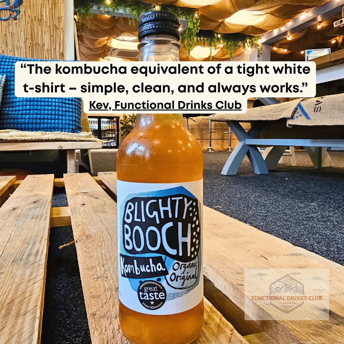 Blighty Booch Organic Original raw kombucha on a wooden pallet table in the Otley taproom, with Kev's tasting note: "The kombucha equivalent of a tight white t-shirt – simple, clean, and always works."