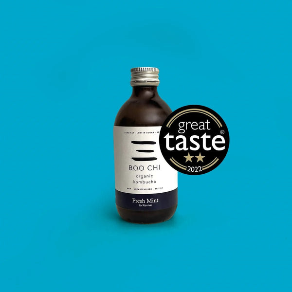 A bottle of Boo Chi Fresh Mint raw kombucha on a bright blue background with its Great Taste 2022 award badge.