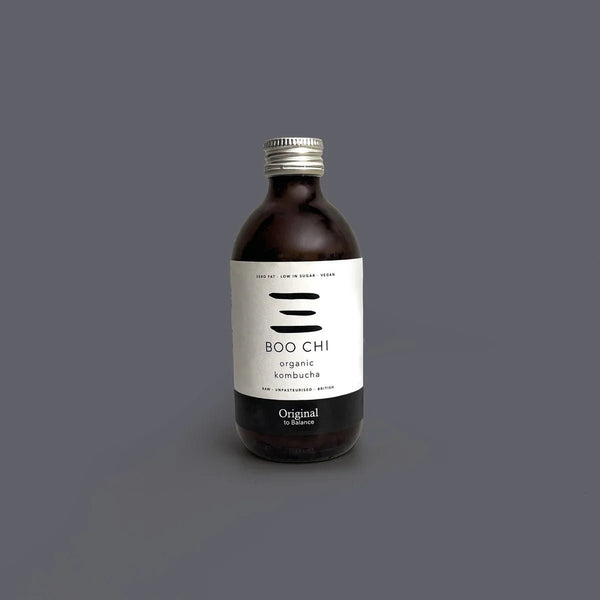 A bottle of Boo Chi Original raw kombucha on a plain grey background.