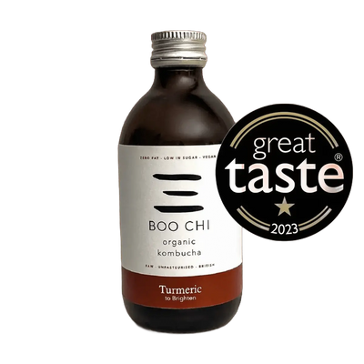 Boo Chi Turmeric & Black Pepper raw kombucha in an amber 330ml glass bottle with a silver cap and a white label with a rust red flavour band, shown with its Great Taste 2023 award badge.