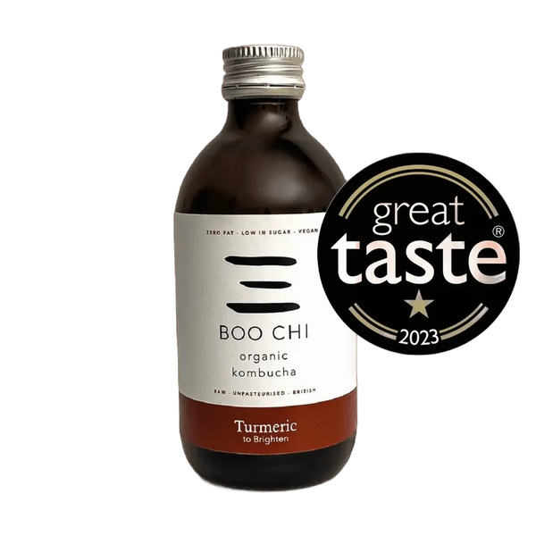 Boo Chi Turmeric & Black Pepper raw kombucha in an amber 330ml glass bottle with a silver cap and a white label with a rust red flavour band, shown with its Great Taste 2023 award badge.
