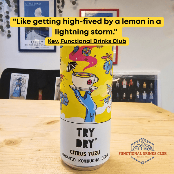 A can of Counter Culture Citrus Yuzu raw kombucha on a wooden table in front of framed Otley art prints, with Kev's tasting note: "Like getting high-fived by a lemon in a lightning storm."