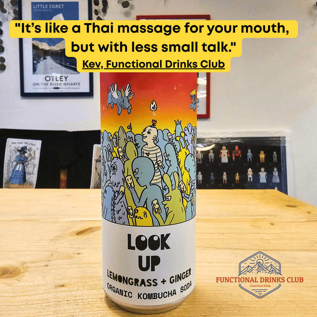 A can of Counter Culture Lemongrass & Ginger raw kombucha on a wooden table in front of framed Otley art prints, with Kev's tasting note: "It's like a Thai massage for your mouth, but with less small talk."