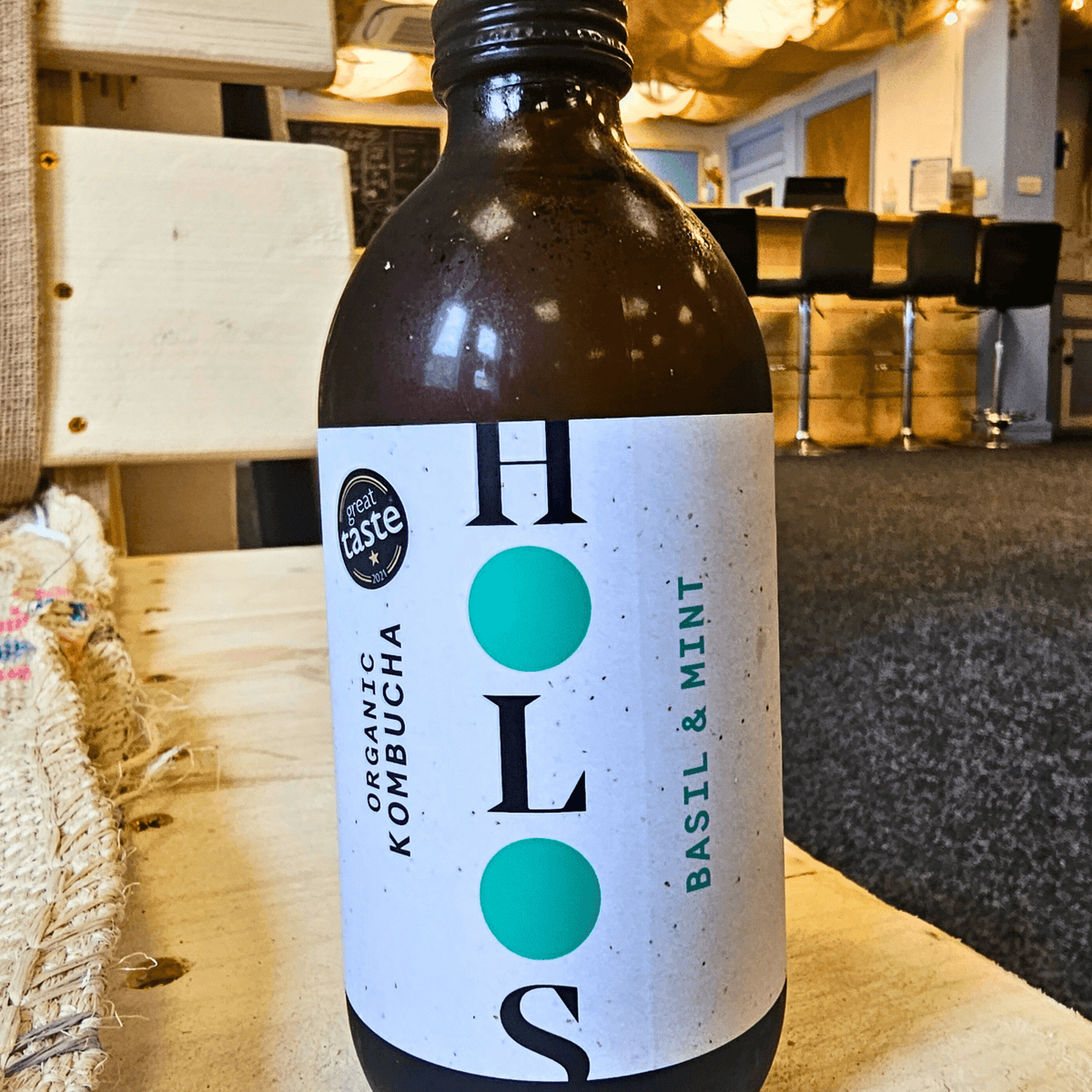 A bottle of HOLOS Basil & Mint raw kombucha on a table in the Otley taproom.