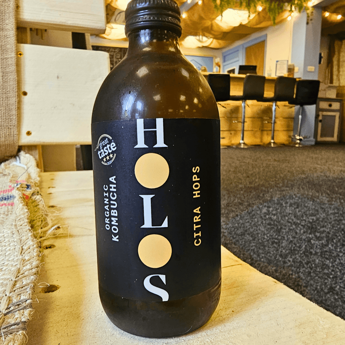 A bottle of HOLOS Citra Hops raw kombucha on a table in the Otley taproom.