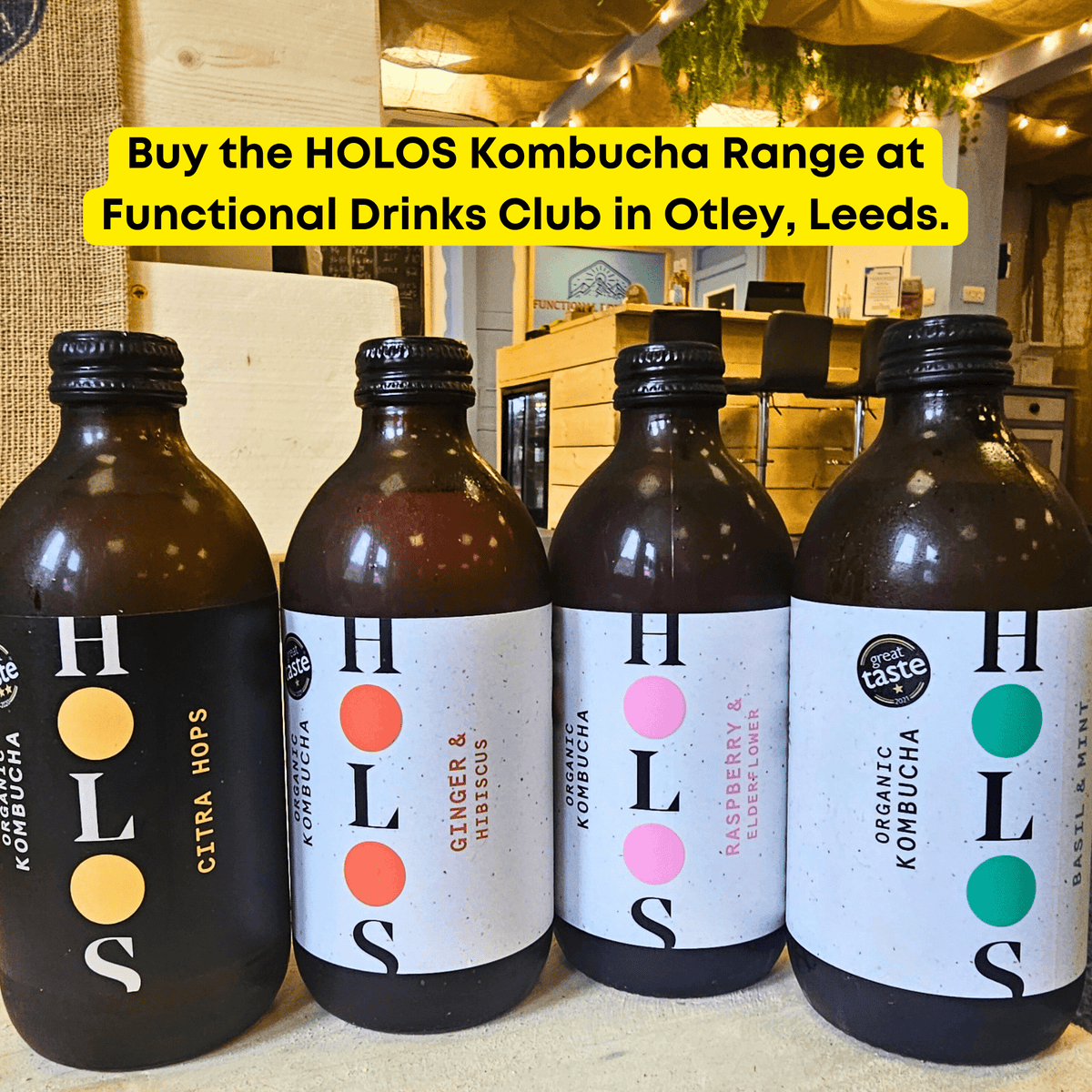 The HOLOS raw kombucha range, Citra Hops, Ginger & Hibiscus, Raspberry & Elderflower and Basil & Mint, lined up in the Otley taproom under a yellow banner saying the range is available to buy in Otley, Leeds.