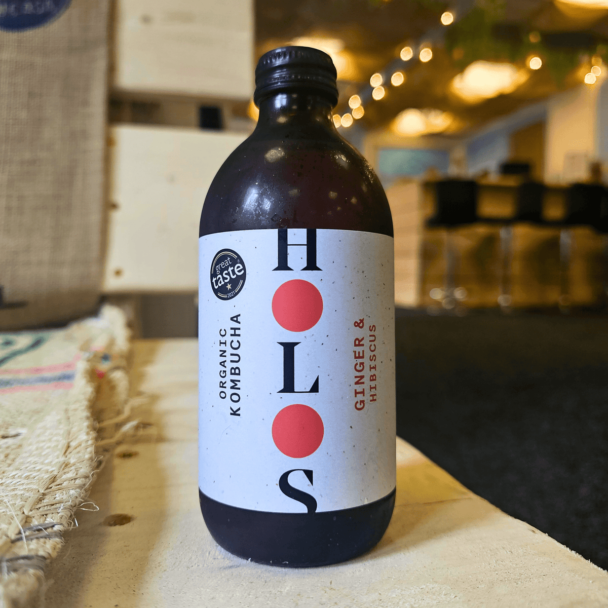 A bottle of HOLOS Ginger & Hibiscus raw kombucha on a table in the Otley taproom.