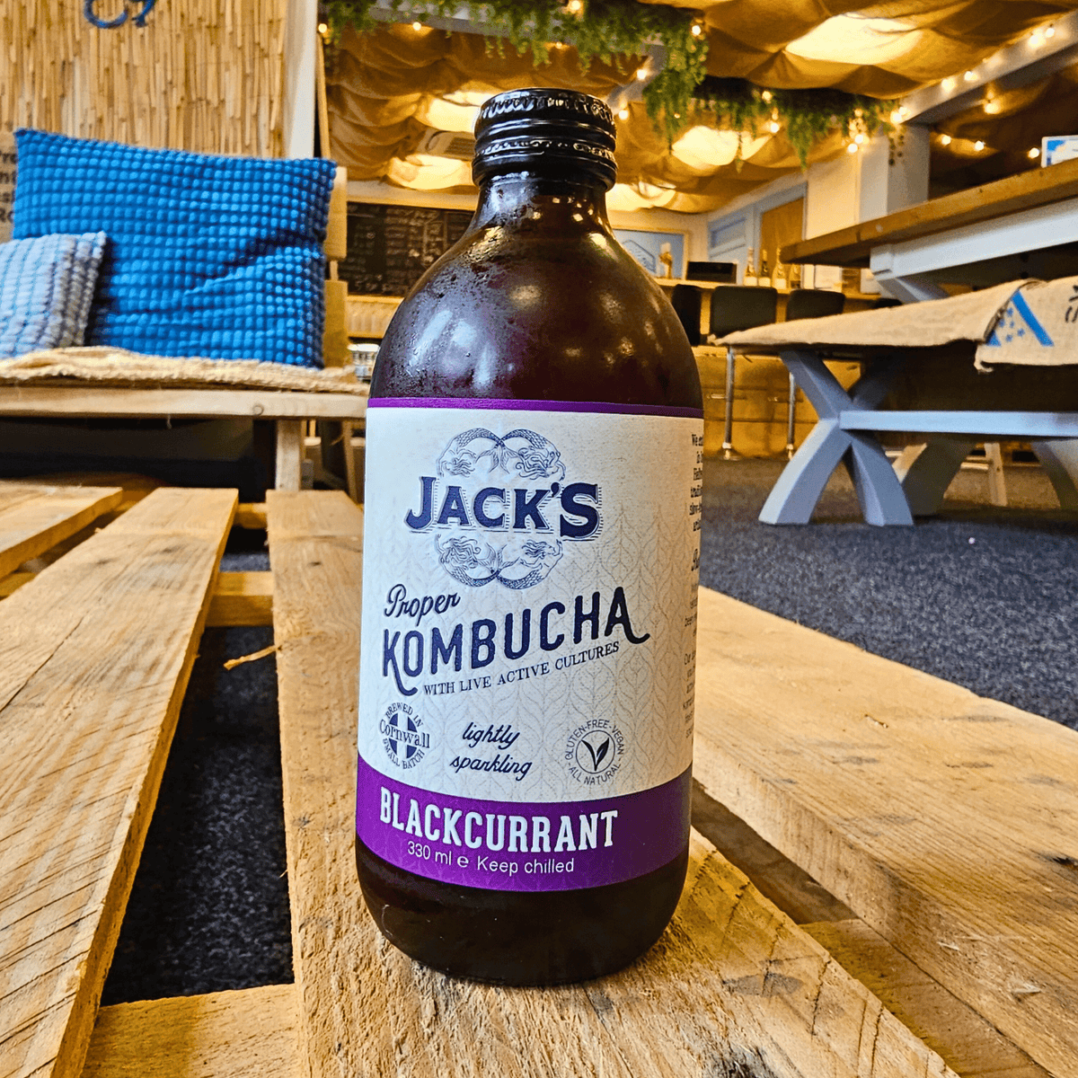 A bottle of Jack's Blackcurrant raw kombucha on a wooden pallet table in the Otley taproom.