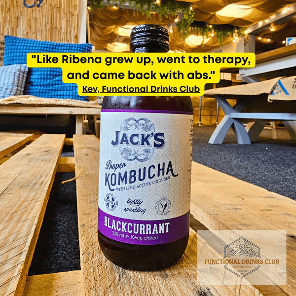 Jack's Blackcurrant raw kombucha on a wooden pallet table in the Otley taproom, with Kev's tasting note: "Like Ribena grew up, went to therapy, and came back with abs."