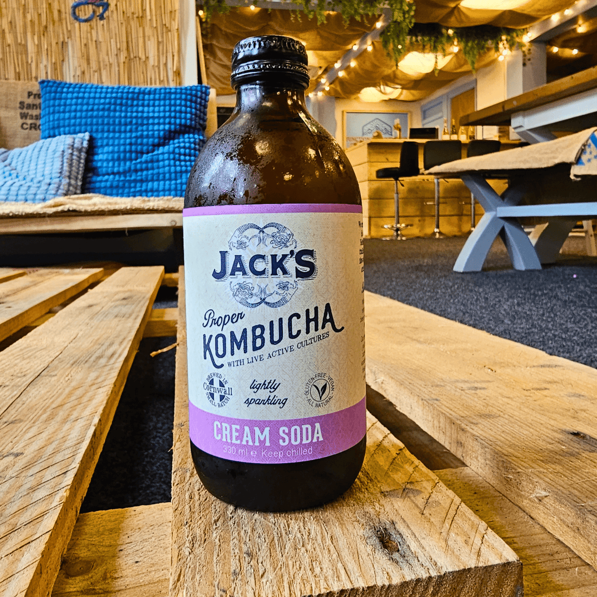 A bottle of Jack's Cream Soda raw kombucha on a wooden pallet table in the Otley taproom.