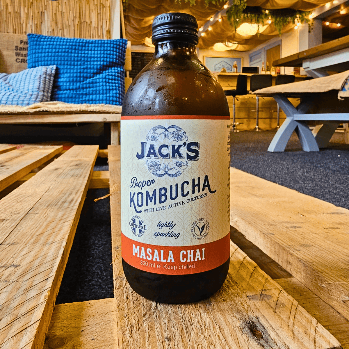 A bottle of Jack's Masala Chai raw kombucha on a wooden pallet table in the Otley taproom.