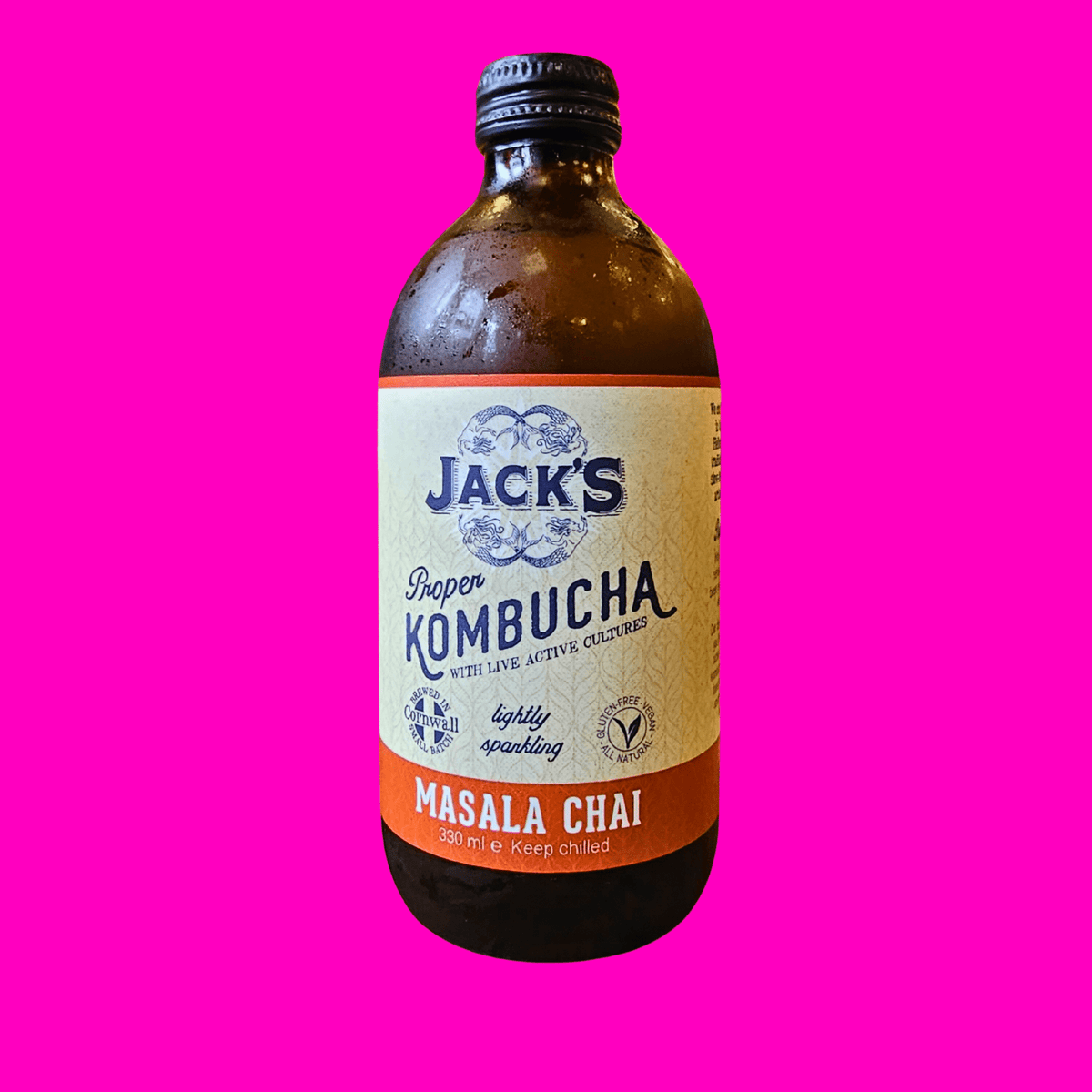 A bottle of Jack's Masala Chai raw kombucha on a hot pink background.