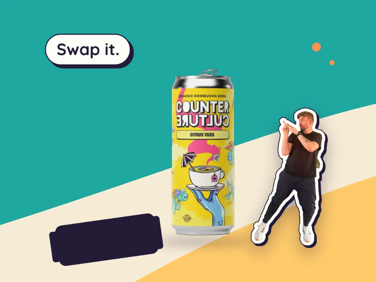 A Counter Culture kombucha can standing tall beside a knocked-over fizzy pop can, with Kev mid-kick