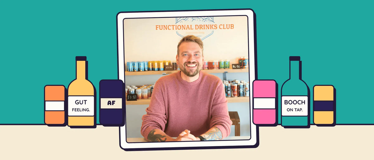 Kev Gillespie smiling at the counter of the Otley taproom, framed between illustrated bottles of Gut Feeling, AF beer and kombucha on tap