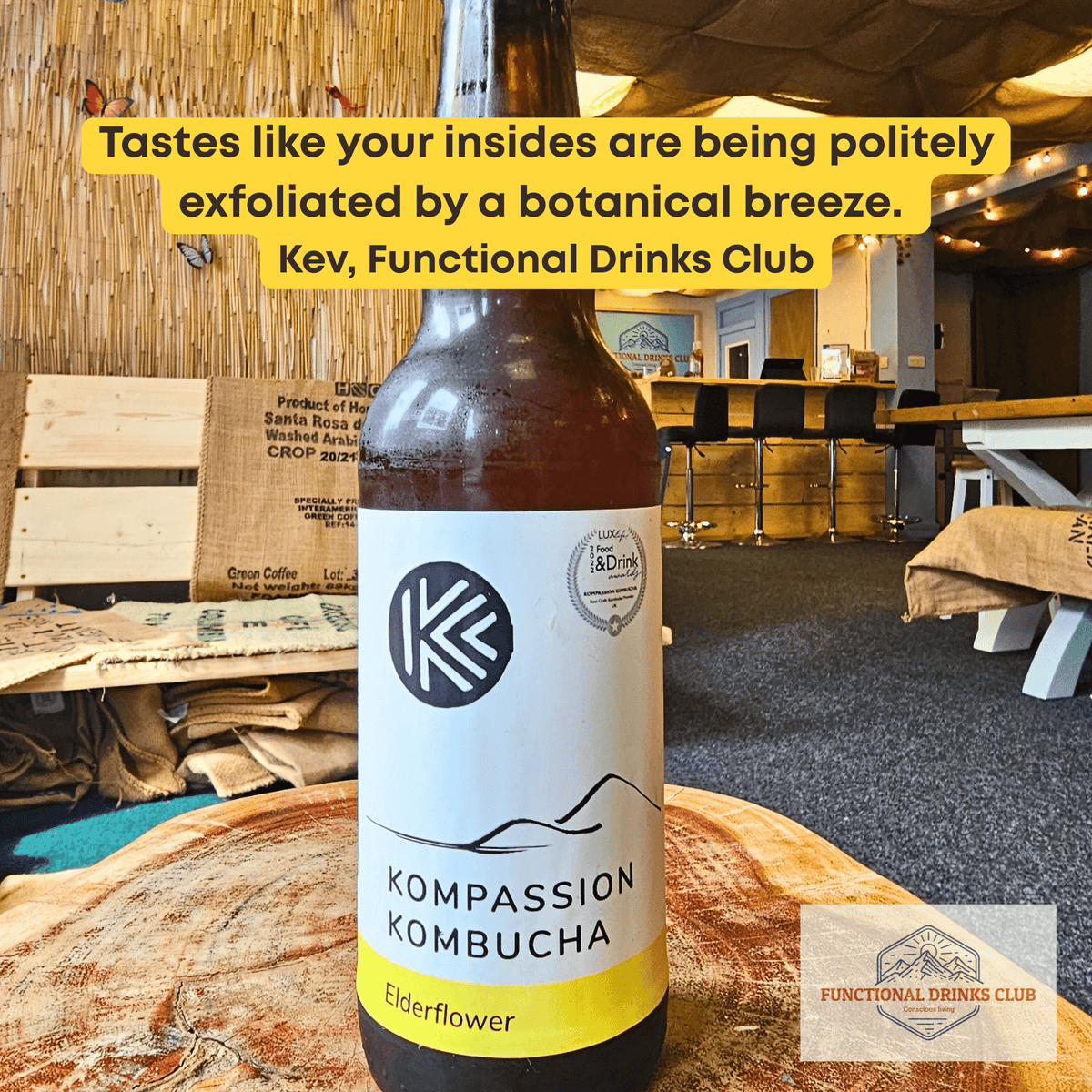 Kompassion Elderflower raw kombucha on a tree-trunk table in the Otley taproom, with Kev's tasting note.
