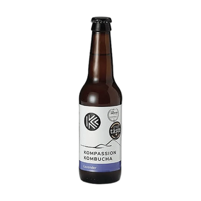 Kompassion Lavender raw kombucha in a tall amber 330ml glass bottle with a black cap and a white label with a violet flavour band and award badges.