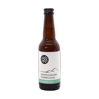 Kompassion Sarsaparilla Root raw kombucha in a tall amber 330ml glass bottle with a black cap and a white label with a sea green flavour band.