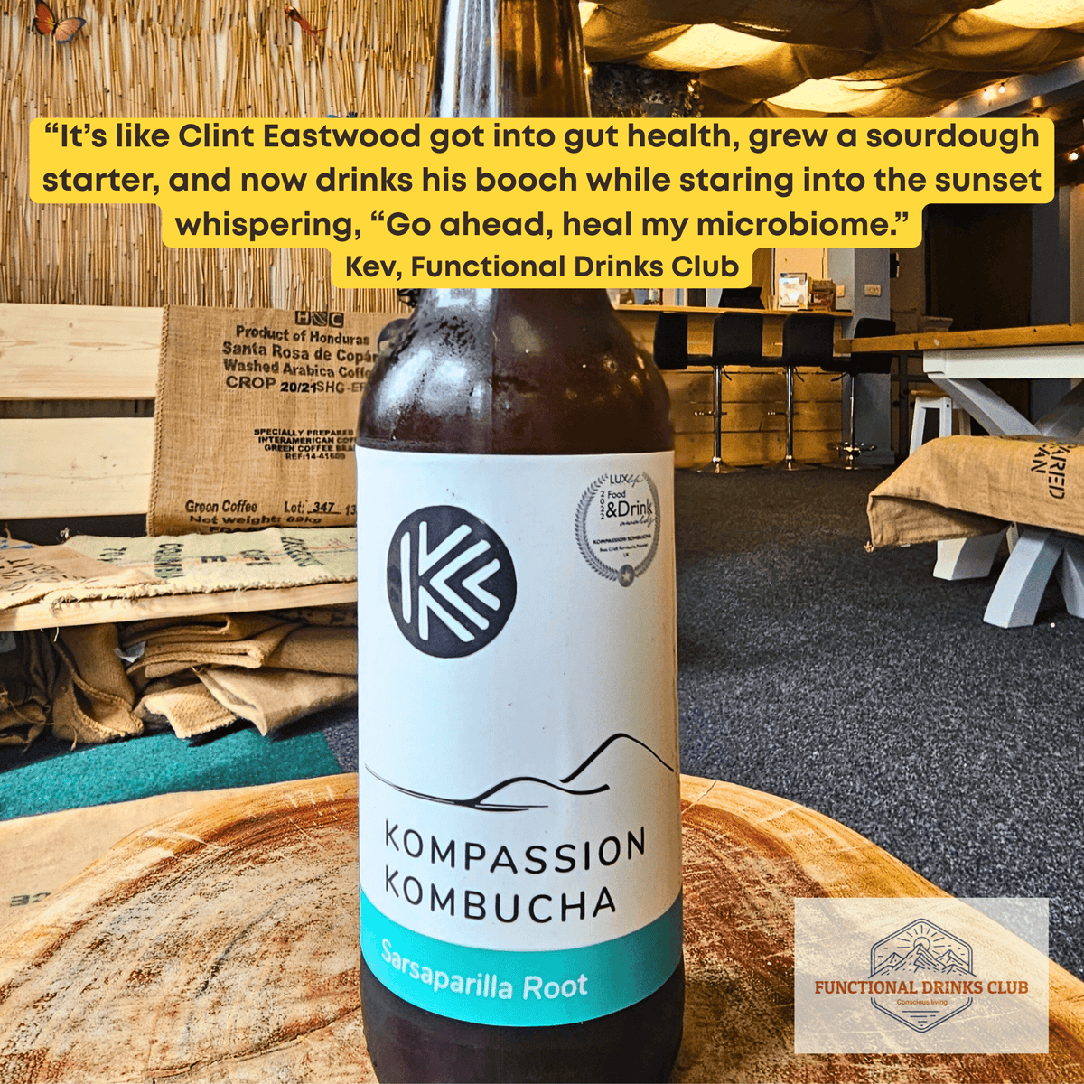 Kompassion Sarsaparilla Root raw kombucha on a tree-trunk table in the Otley taproom, with Kev's tasting note.