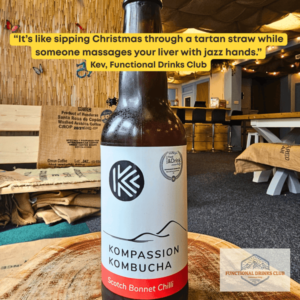 Kompassion Scotch Bonnet Chilli raw kombucha on a tree-trunk table in the Otley taproom, with Kev's tasting note: "It's like sipping Christmas through a tartan straw while someone massages your liver with jazz hands."