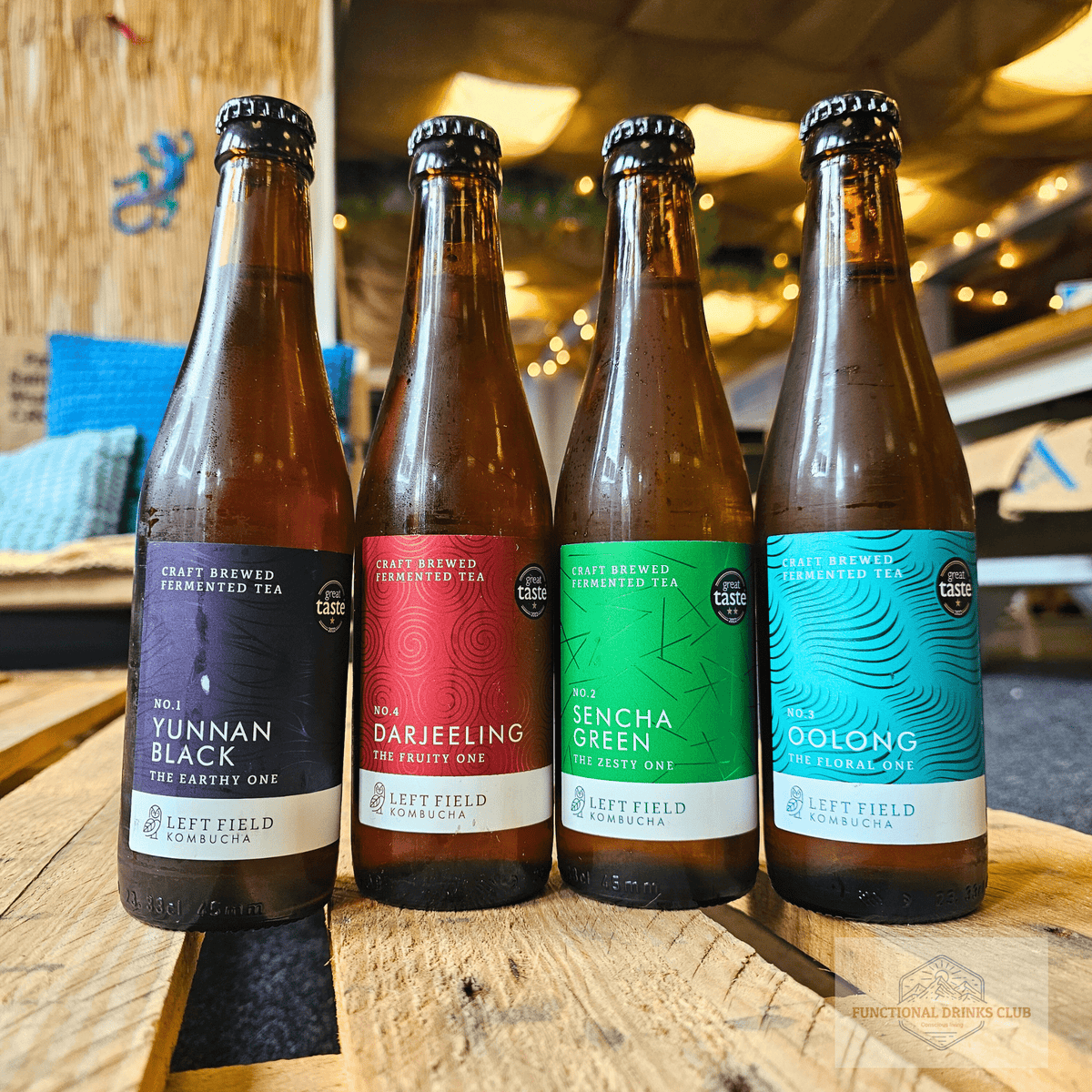 The four Left Field raw kombuchas, No.1 Yunnan Black, No.4 Darjeeling, No.2 Sencha Green and No.3 Oolong, lined up on a wooden pallet table in the Otley taproom.