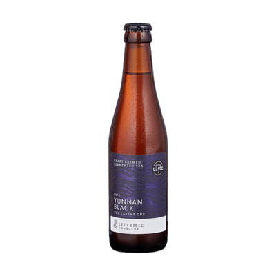 Left Field No.1 Yunnan Black raw kombucha in a tall amber 330ml glass bottle with a black cap and a deep purple wave-patterned label.
