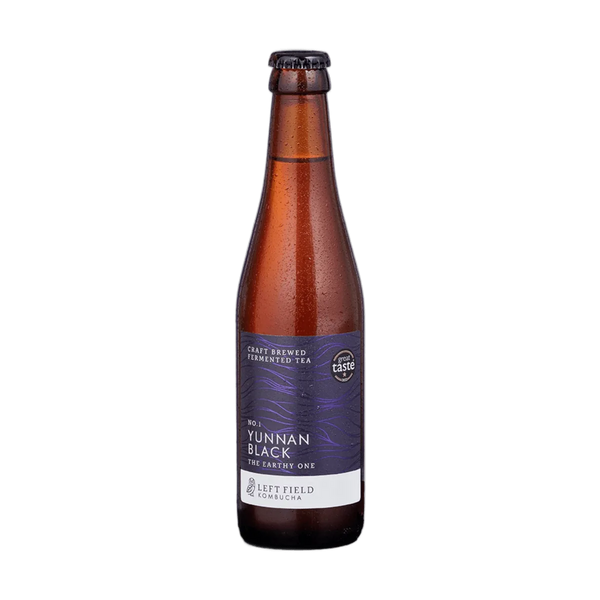Left Field No.1 Yunnan Black raw kombucha in a tall amber 330ml glass bottle with a black cap and a deep purple wave-patterned label.