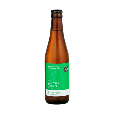 Left Field No.2 Sencha Green raw kombucha in a tall amber 330ml glass bottle with a black cap and a bright green label with a fine line pattern.