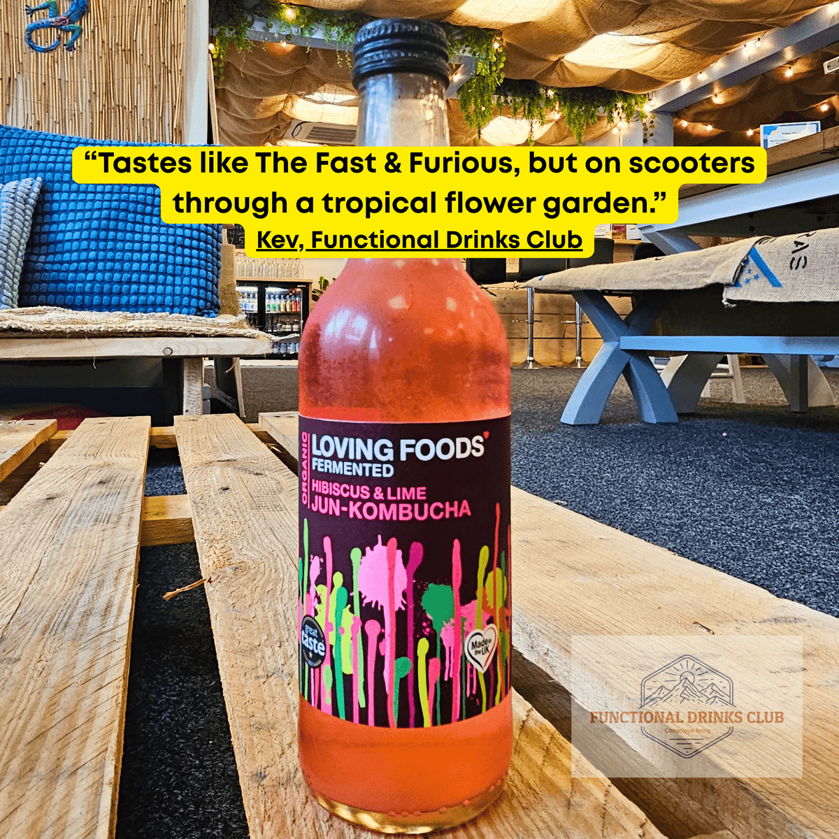 Loving Foods Hibiscus & Lime raw jun kombucha on a wooden pallet table in the Otley taproom, with Kev's tasting note: "Tastes like The Fast & Furious, but on scooters through a tropical flower garden."