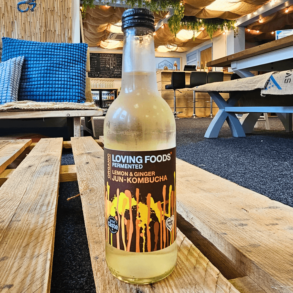 A bottle of Loving Foods Lemon & Ginger raw jun kombucha on a wooden pallet table in the Otley taproom.