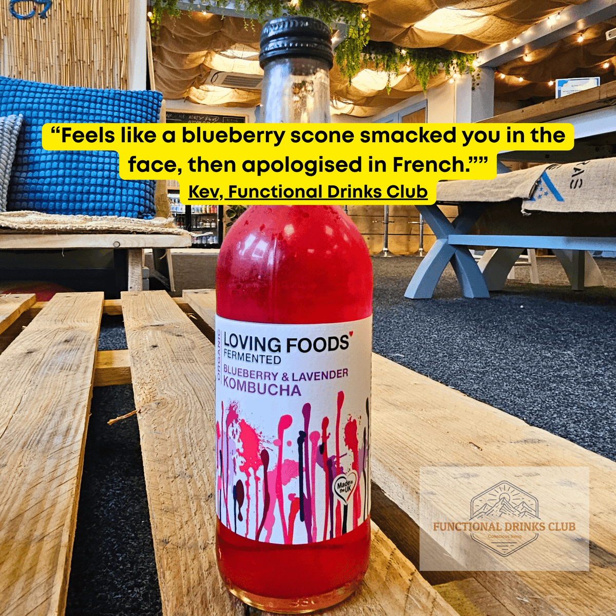 Loving Foods Blueberry & Lavender raw kombucha on a wooden pallet table in the Otley taproom, with Kev's tasting note: "Feels like a blueberry scone smacked you in the face, then apologised in French."