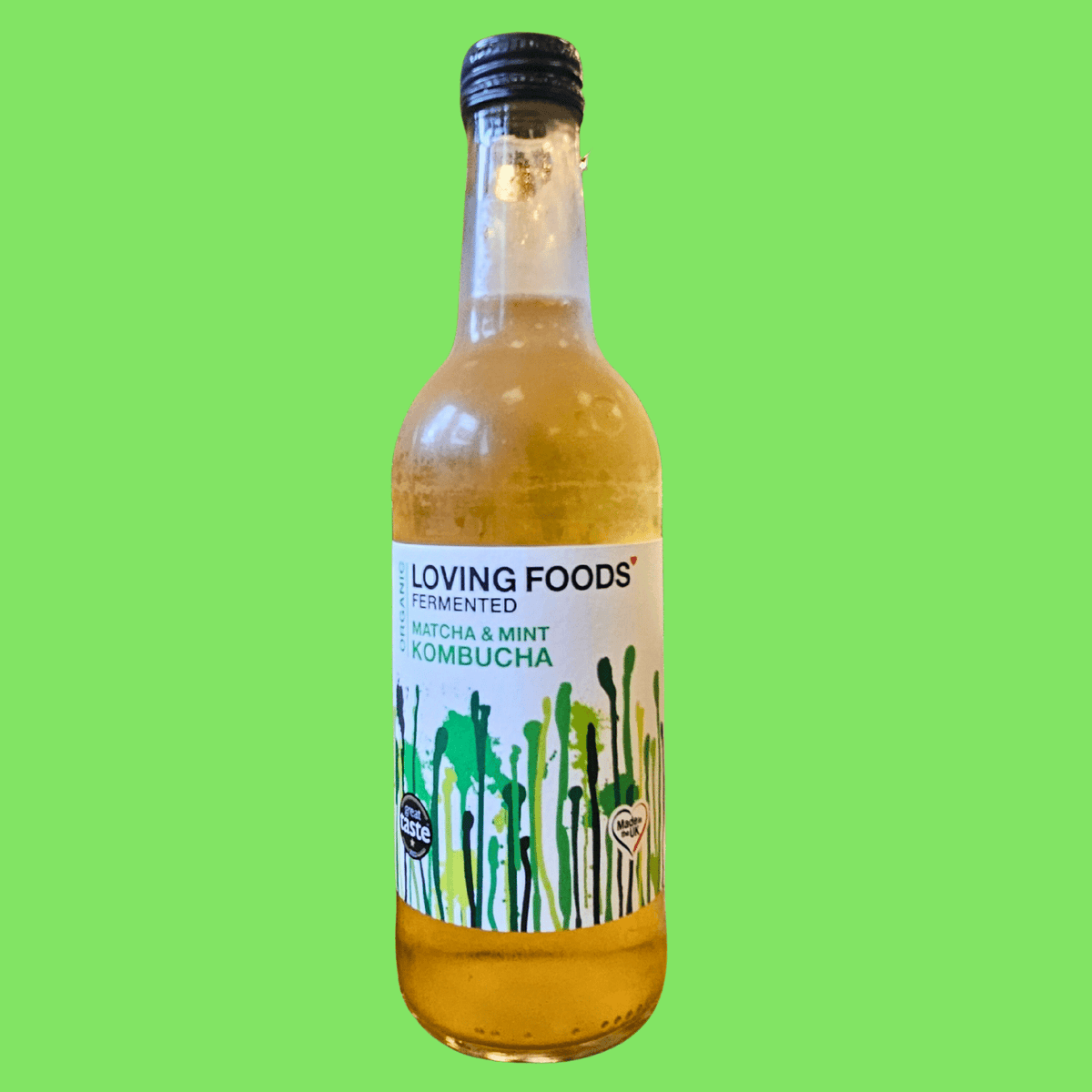 A bottle of Loving Foods Matcha & Mint raw kombucha on a bright green background.