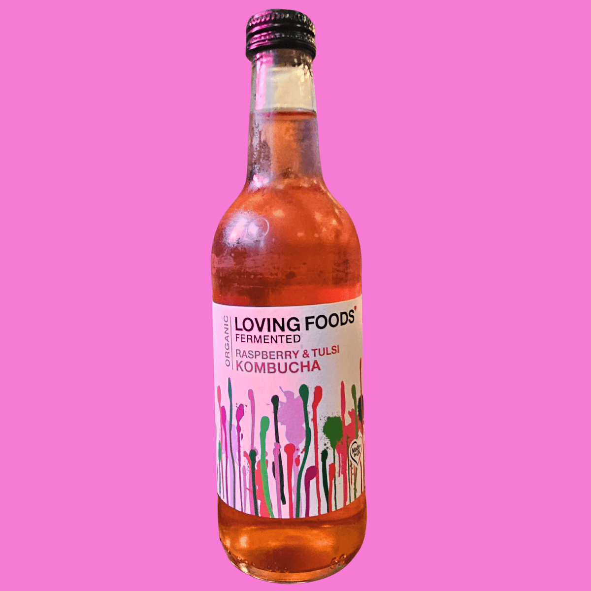 A bottle of Loving Foods Raspberry & Tulsi raw kombucha on a bright pink background.
