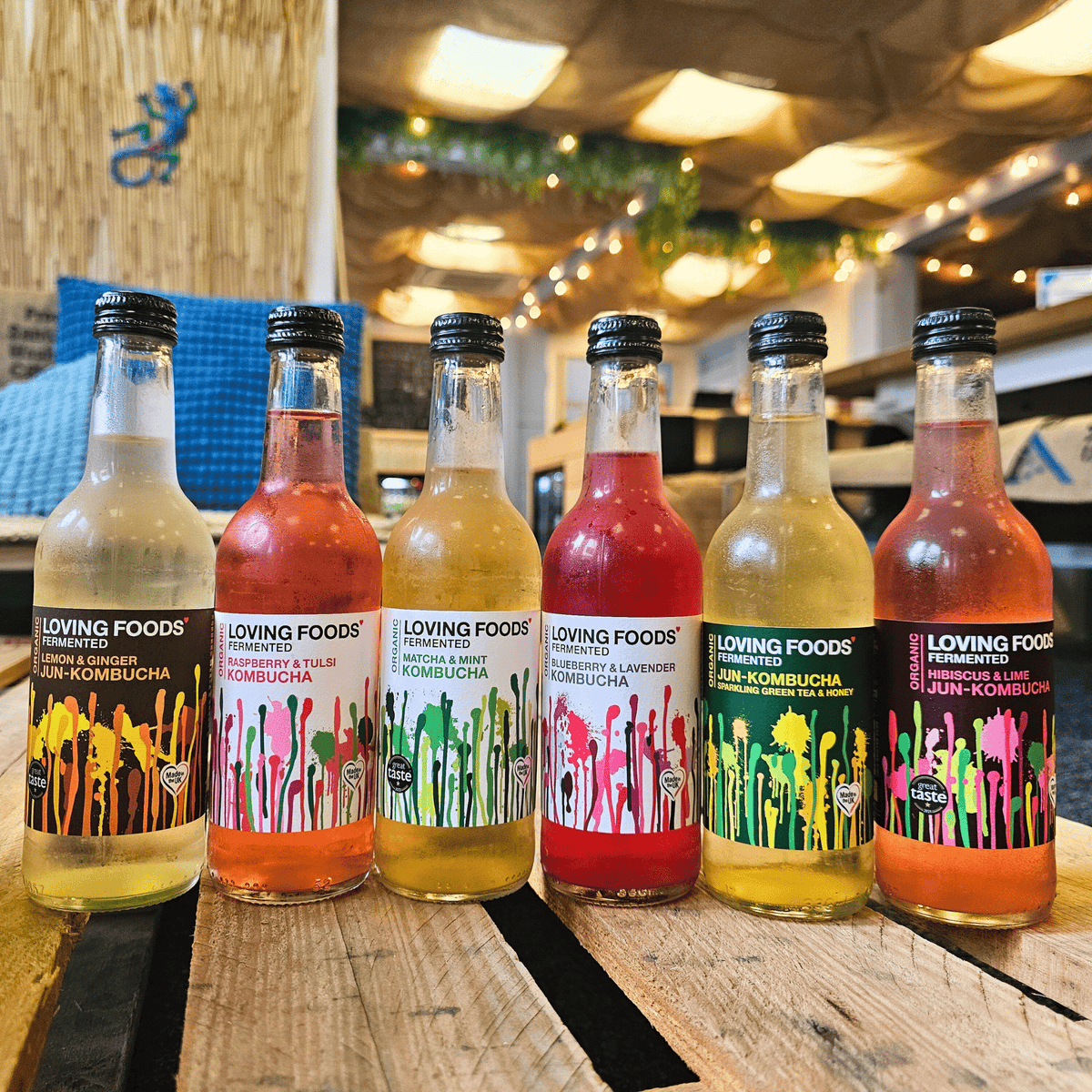 Six Loving Foods raw kombucha and jun kombucha flavours lined up on a wooden pallet table in the Otley taproom.