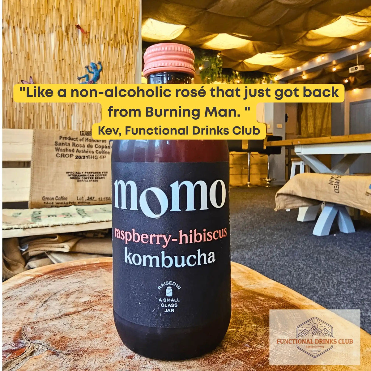 MOMO Raspberry & Hibiscus raw kombucha on a tree-trunk table in the Otley taproom, with Kev's tasting note: "Like a non-alcoholic rosé that just got back from Burning Man."
