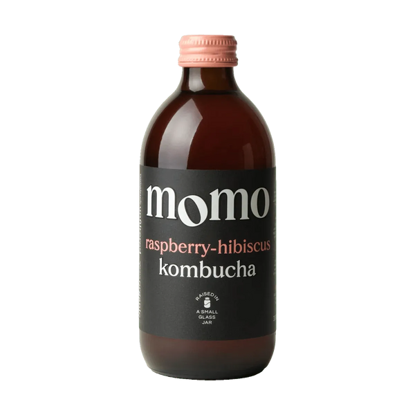 MOMO Raspberry & Hibiscus raw kombucha in an amber glass bottle with a pink cap and a black label with pink lettering.