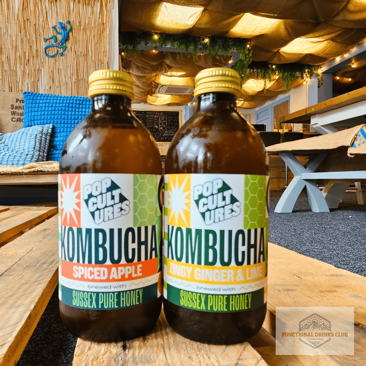 Pop Cultures Spiced Apple and Zingy Ginger & Lime raw jun kombucha side by side on a wooden pallet table in the Otley taproom.