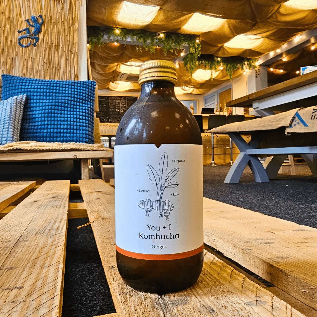 A bottle of You + I Ginger raw kombucha on a wooden pallet table in the Otley taproom.