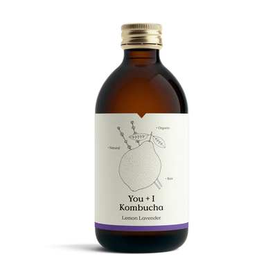 You + I Lemon & Lavender raw kombucha in an amber glass bottle with a gold cap and a cream label with a botanical line drawing and a purple band.