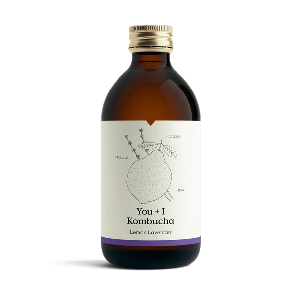 You + I Lemon & Lavender raw kombucha in an amber glass bottle with a gold cap and a cream label with a botanical line drawing and a purple band.