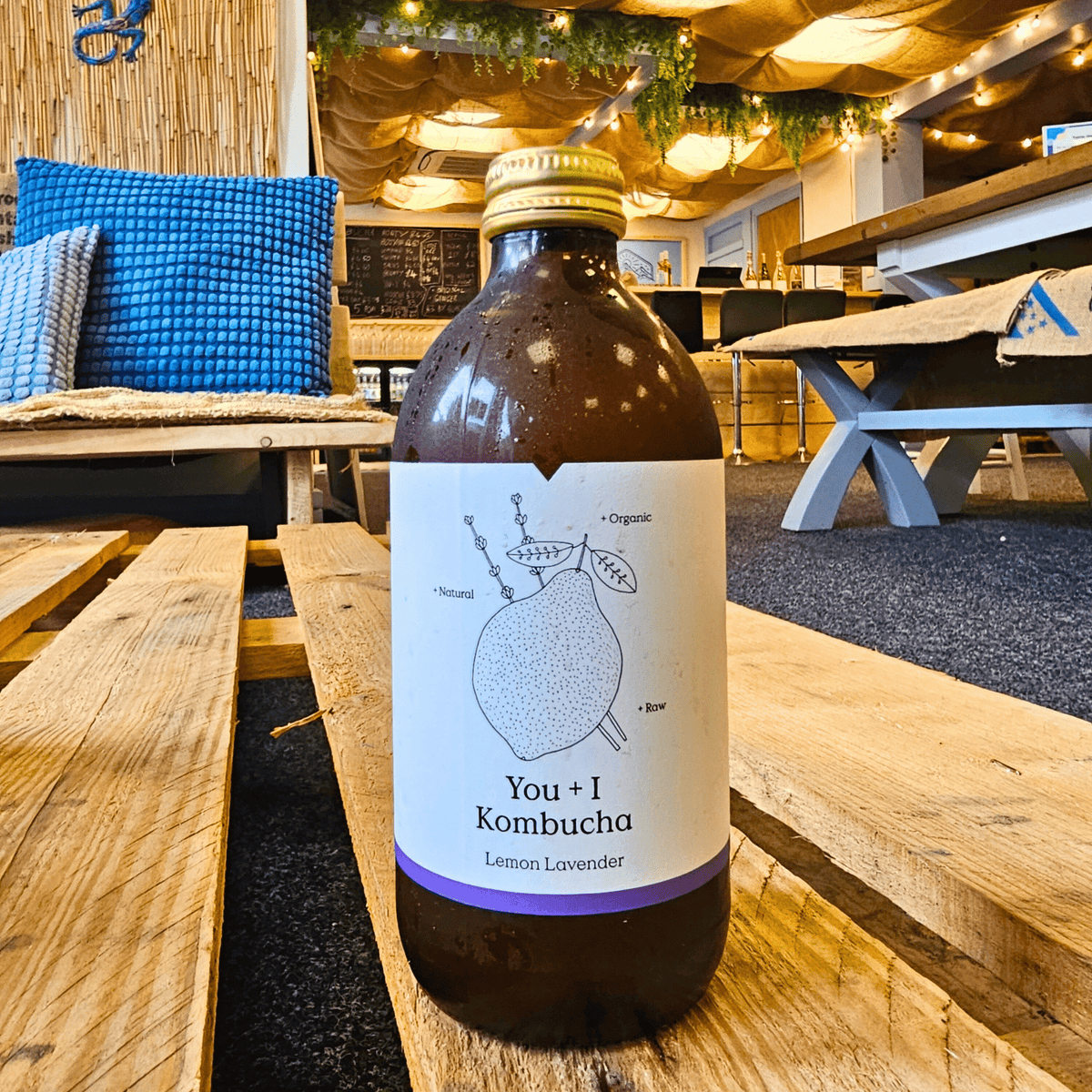 A bottle of You + I Lemon & Lavender raw kombucha on a wooden pallet table in the Otley taproom.