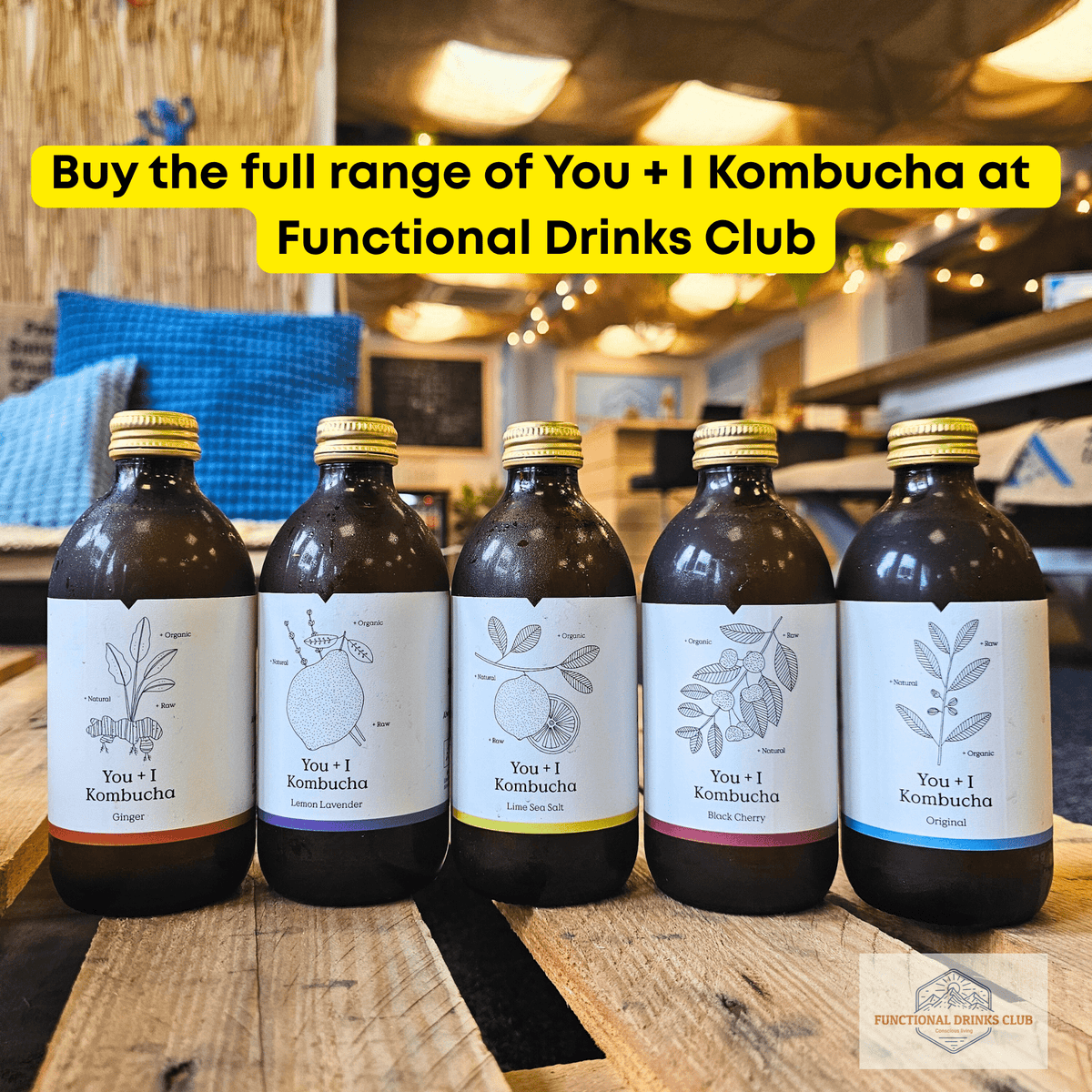 The full You + I raw kombucha range, Ginger, Lemon & Lavender, Lime & Sea Salt, Black Cherry and Original, lined up on a wooden pallet table in the Otley taproom under a yellow banner: "Buy the full range of You + I Kombucha at Functional Drinks Club".