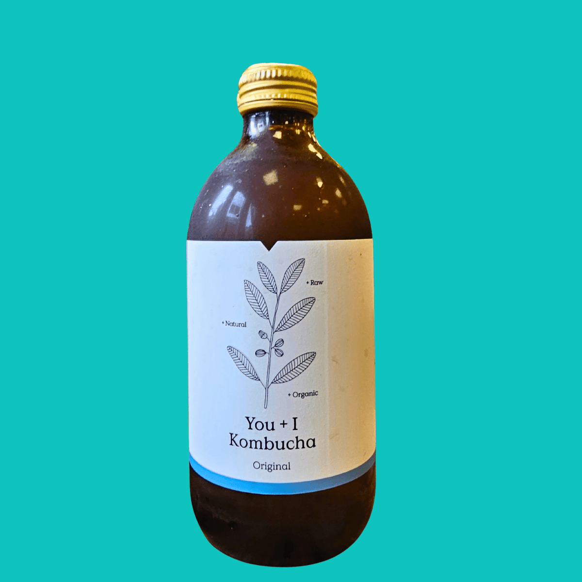 A bottle of You + I Original raw kombucha on a teal background.